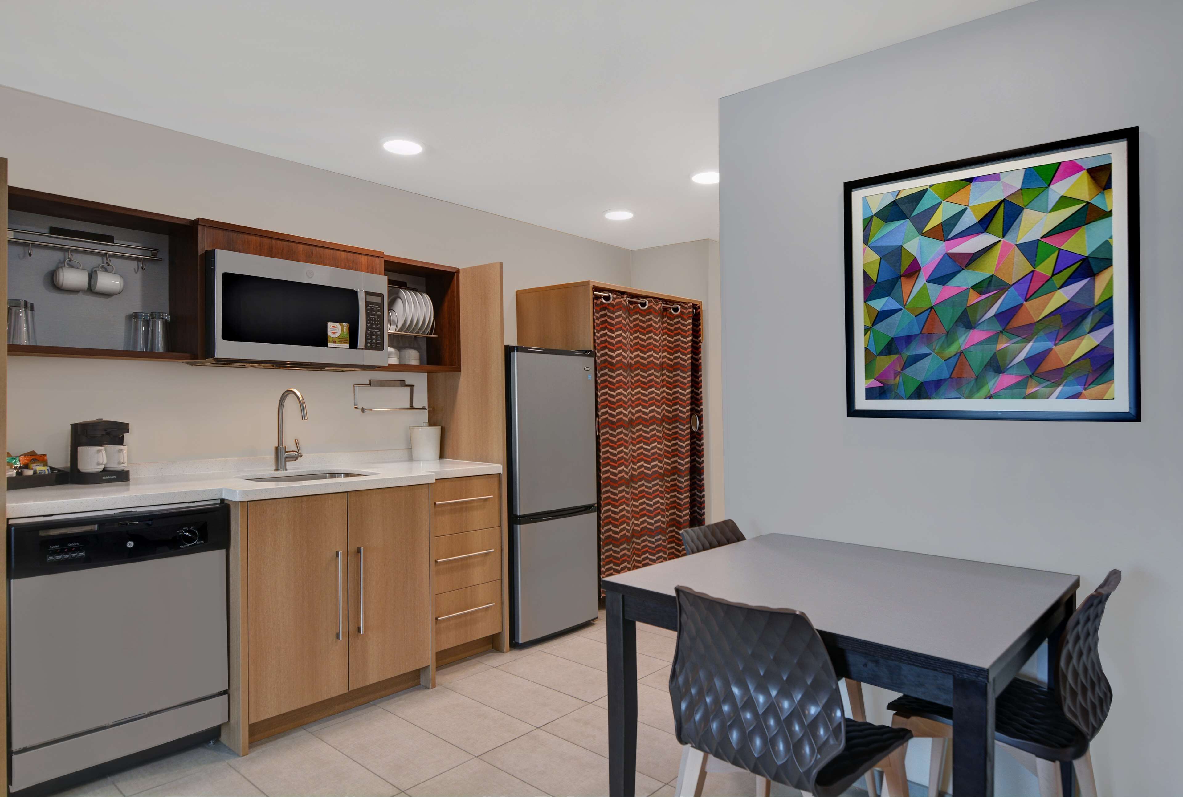A modern kitchen with a dishwasher, microwave, refrigerator, and a dining table with chairs.