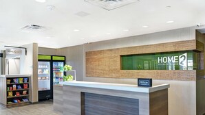A hotel reception area with a modern design, including a reception desk, a glass display, and a snack vending machine. - Home2 Suites by Hilton Richmond Hilll Savannah I-95 (Richmond Hill)