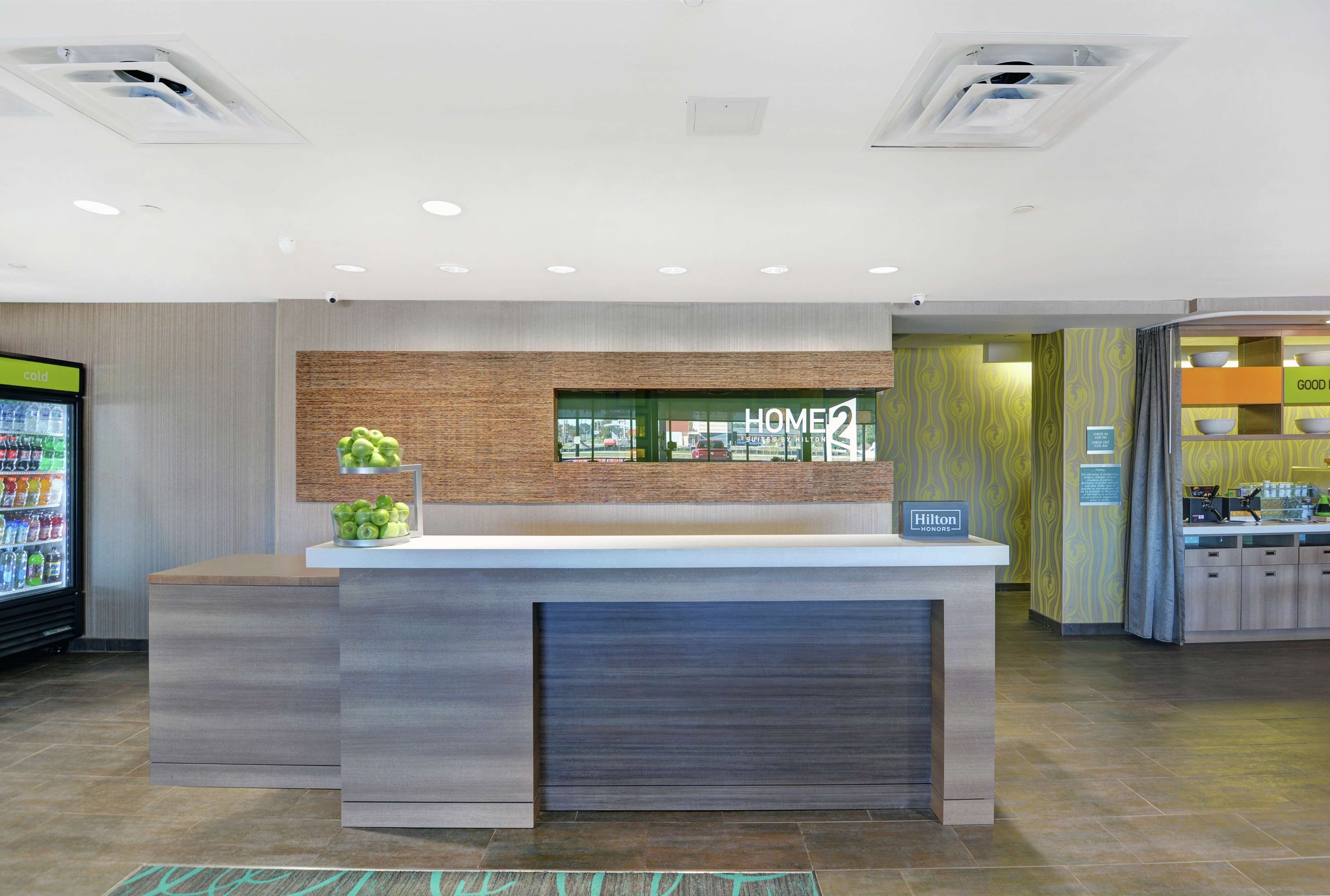 A modern hotel reception area with a reception desk, a digital display, and a vending machine.
