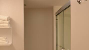 A modern bathroom with a toilet, a glass shower enclosure, and a sink with a towel rack.