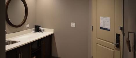 A small, well-lit bathroom with a sink, mirror, and toilet.