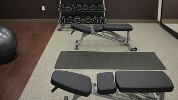 A gym with weightlifting equipment, including dumbbells and benches.