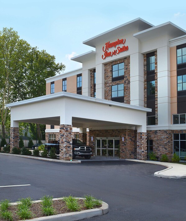 A Hampton Inn & Suites hotel with a covered entrance, brick facade, and large windows.