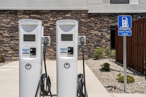 Two EV charging stations labeled 'EV INSTITUTE' with a sign indicating 'ELECTRIC VEHICLE CHARGING' nearby.
