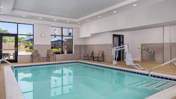 Una piscina interior con agua cristalina, rodeada de sillones de descanso y una tumbona.