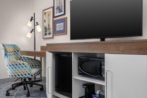 A modern office space with a large flat-screen TV, a patterned office chair, and a coffee machine. - Hampton Inn Baltimore Bayview Campus (Baltimore)