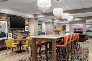 A restaurant with a long counter, multiple chairs, and a chandelier. - Hampton Inn Baltimore Bayview Campus (Baltimore)