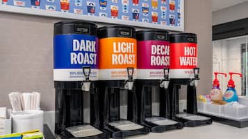 Cuatro dispensadores de café etiquetados como: CAFE OSCURO, CAFE CLARO, DESCAFEINADO y AGUA CALIENTE, cada uno con el nombre de una marca de café.