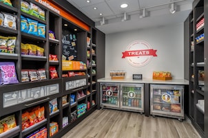 Una sección de snacks y bebidas con estantes llenos de papas fritas, palomitas de maíz y dulces.