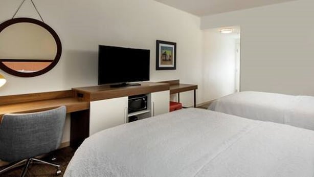 A hotel room with two beds, a desk with a television, a chair, and a microwave. - Hampton Inn Baltimore Bayview Campus (Baltimore)