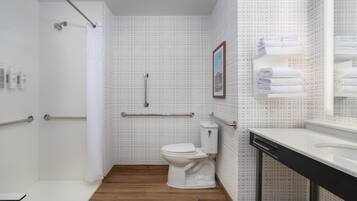 A modern bathroom with a toilet, shower, and a sink with a mirror.
