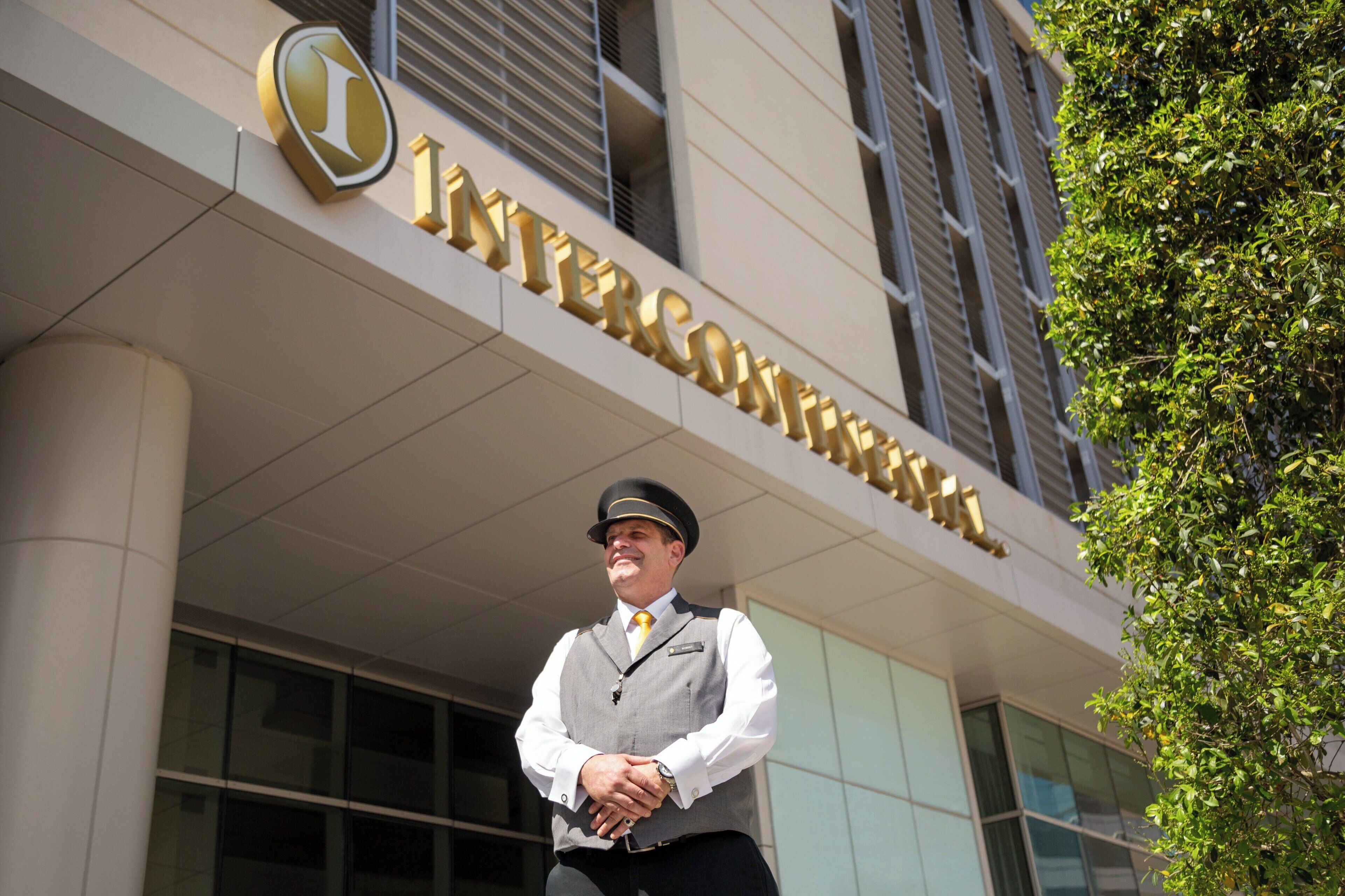 Een man staat voor een gebouw met een bord waarop 'INTERCONTINENTAL' staat.