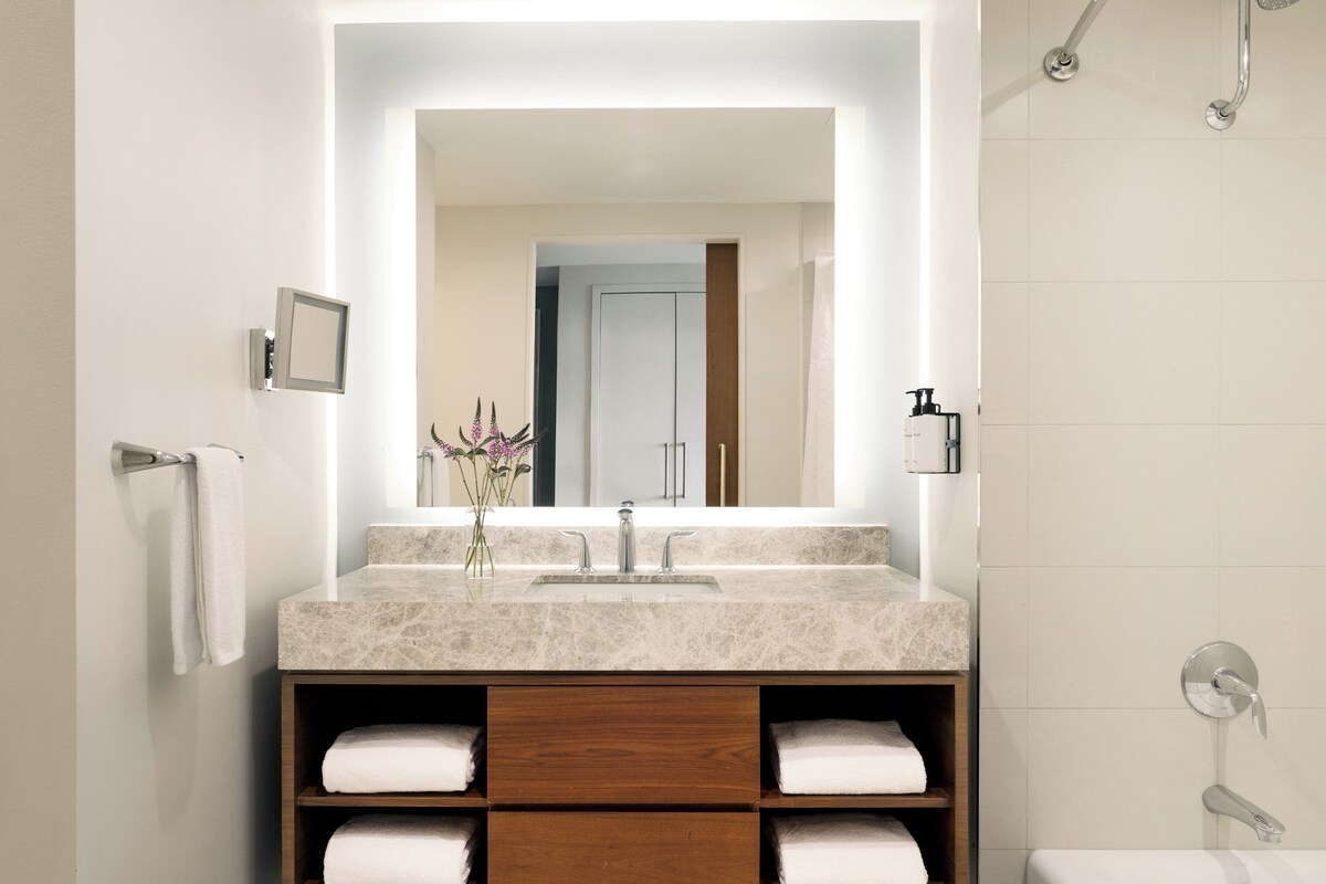 Une salle de bain moderne avec un grand miroir, un lavabo et une douche.