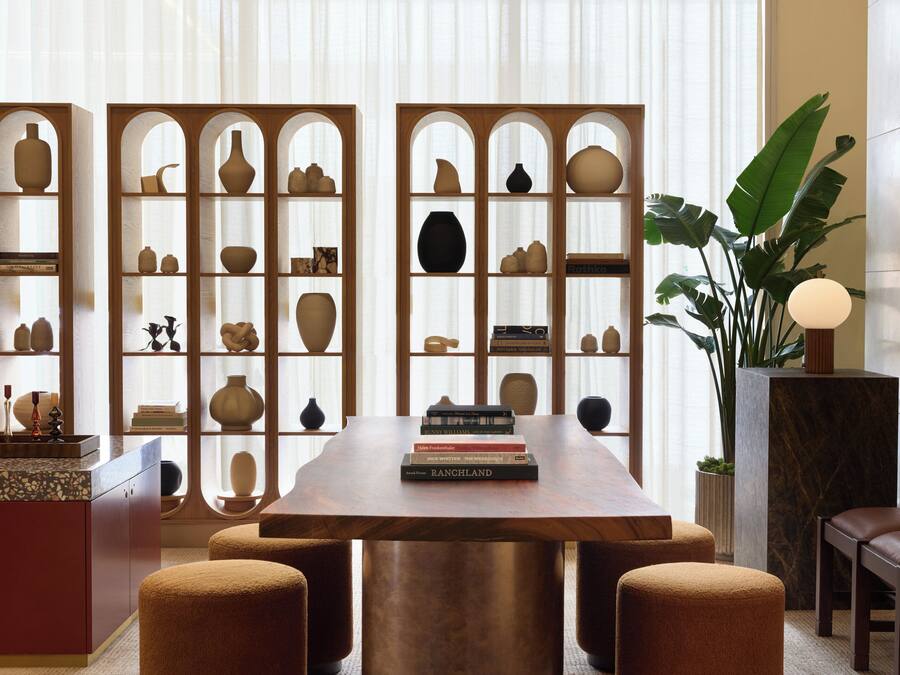 A dining area with a wooden table, cushioned chairs, and a decorative plant.