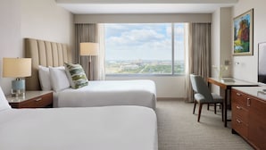 A hotel room with two beds, a desk, a chair, a TV, and a large window with a city view. - InterContinental Houston by IHG (Houston)