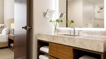 A bathroom with a marble sink, two framed mirrors, a shower, and a towel rack.