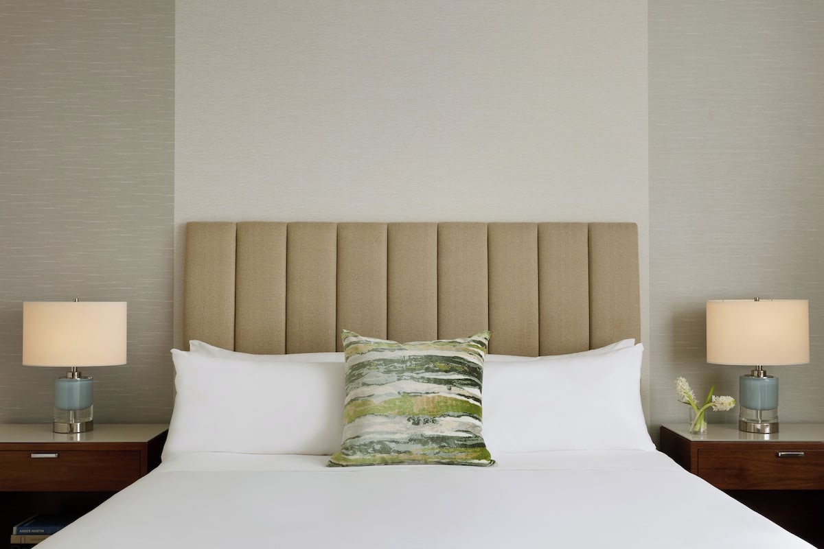 A hotel room with a bed, two bedside tables, and a headboard.