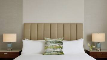 Una habitación de hotel con una cama, dos mesitas de noche y un cabecero.