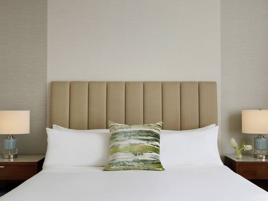 Una habitación de hotel con una cama, dos mesitas de noche y un cabecero.
