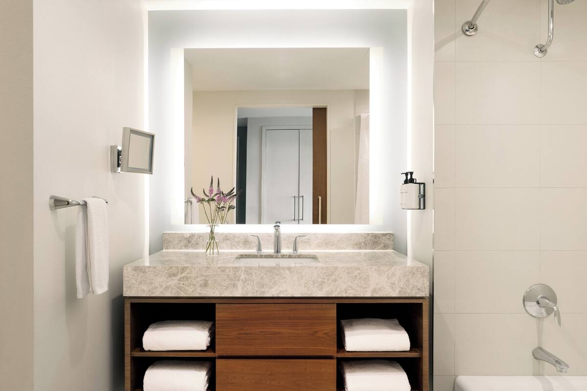 A modern bathroom with a large mirror, a sink, and a shower.