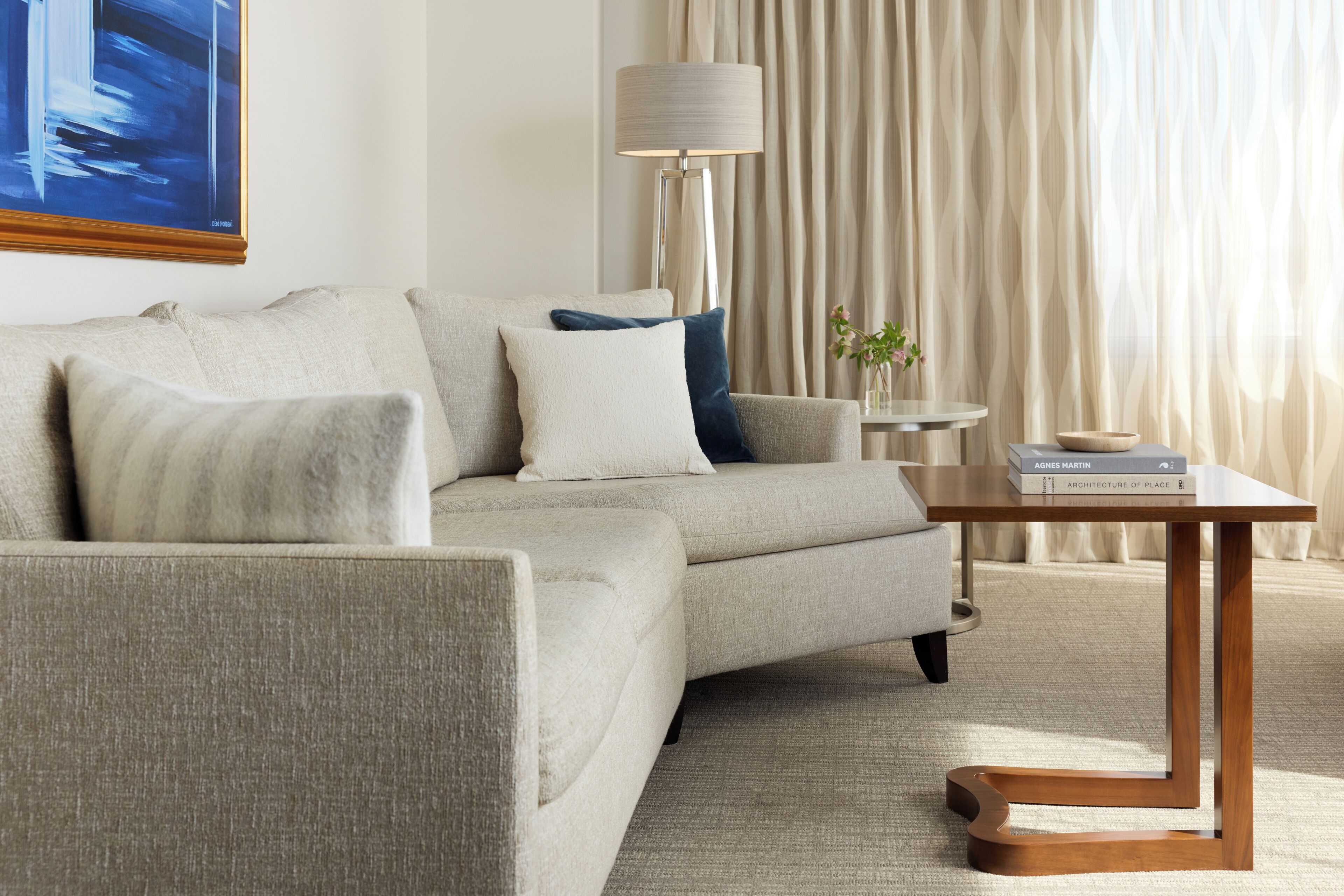 A modern living room with a sofa, a side table, a lamp, and a book on the table.