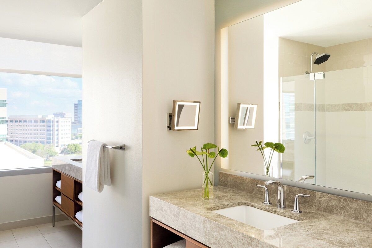 Une salle de bain moderne avec un grand miroir, un lavabo et une douche.