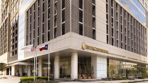 A modern building with a prominent 'InterContinental' sign, large windows, and a flag display. - InterContinental Houston by IHG (Houston)