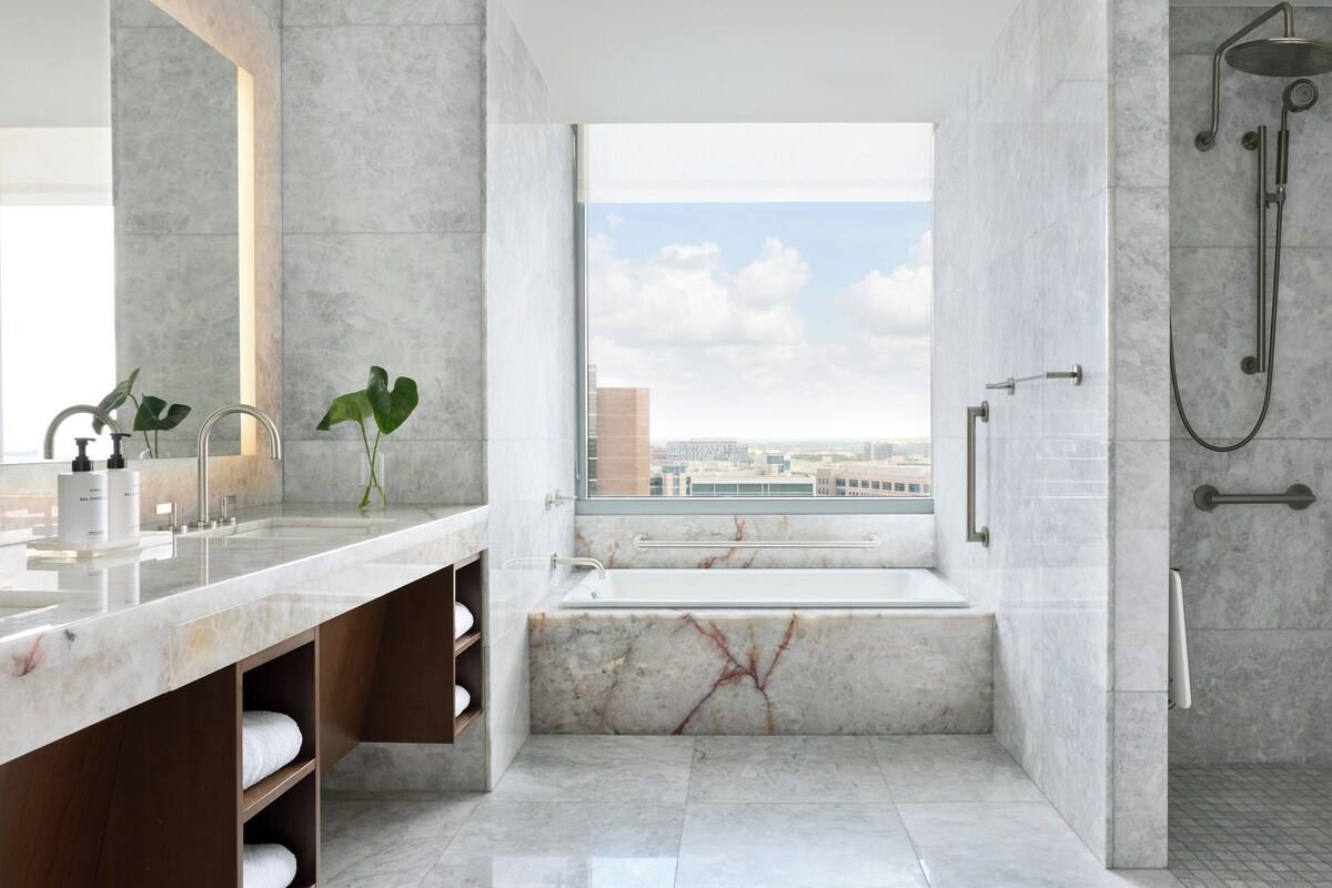 Une salle de bain moderne dotée d’une grande fenêtre, d’une baignoire et d’une douche.