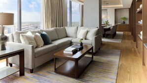 A modern hotel room with a sectional sofa, a coffee table, and a view of the city. - InterContinental Houston by IHG (Houston)