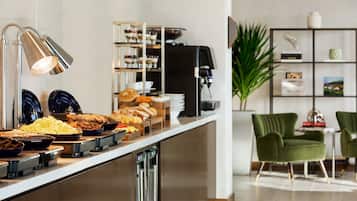 A buffet with various food items, a coffee machine, and a seating area with chairs and a plant.