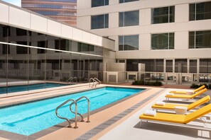 A swimming pool with lounge chairs and a glass-enclosed area. - InterContinental Houston by IHG (Houston)
