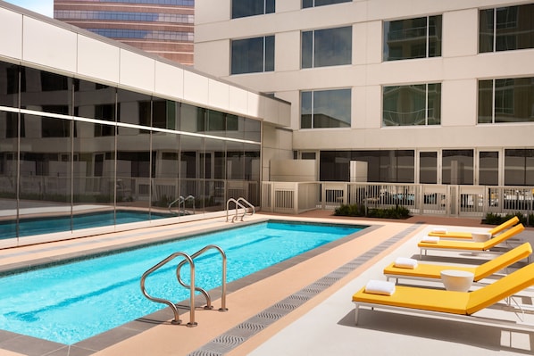 Uma piscina com espreguiçadeiras e área envidraçada.