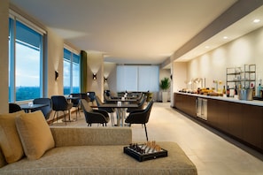 A modern hotel room with a dining area, a sofa, and a chessboard.