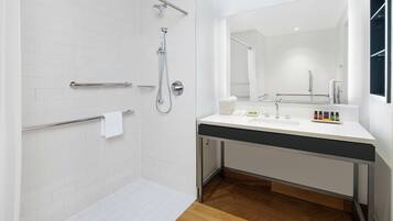 A modern bathroom with a shower, a sink, and a mirror.