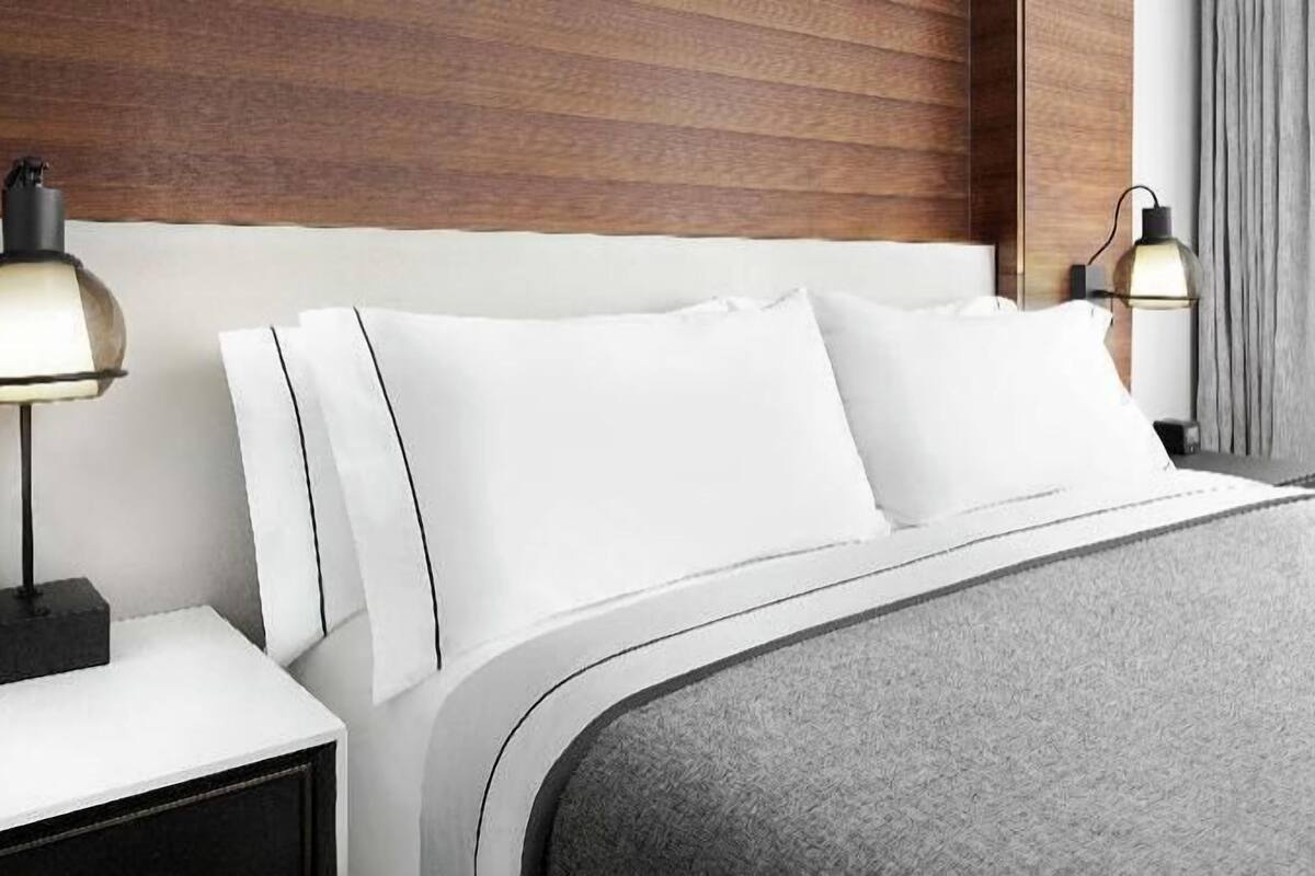 A hotel room with a wooden headboard, white bedding, and two bedside lamps.