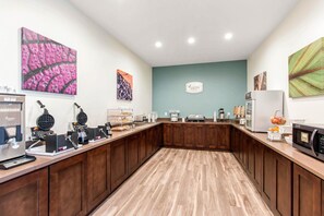 A kitchen area with a wooden counter, waffle maker, coffee machine, and a refrigerator.