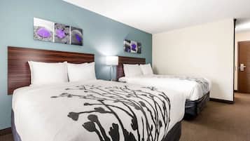 Une chambre d’hôtel avec deux lits, une tête de lit en bois, une table de chevet avec une lampe et des œuvres d’art murales.