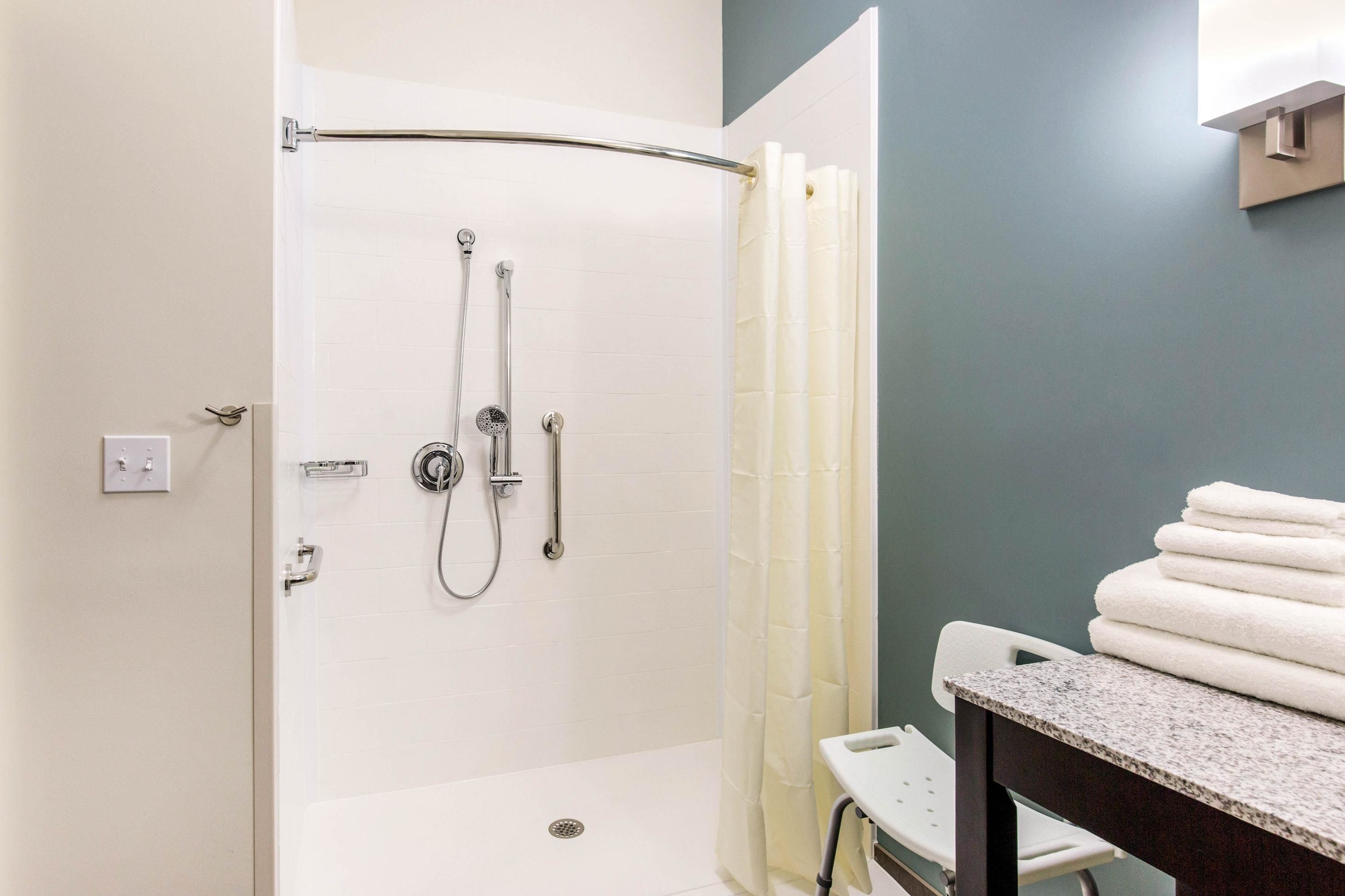 A shower with a glass door, a towel rack, and a small step stool.