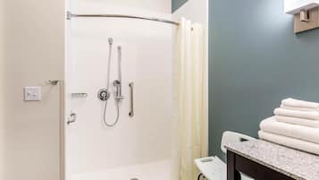 Ducha con puerta de cristal, un perchero y un pequeño taburete.