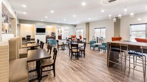 A modern hotel lobby with seating areas, a bar, and a television. - Sleep Inn & Suites South Jacksonville (Jacksonville)
