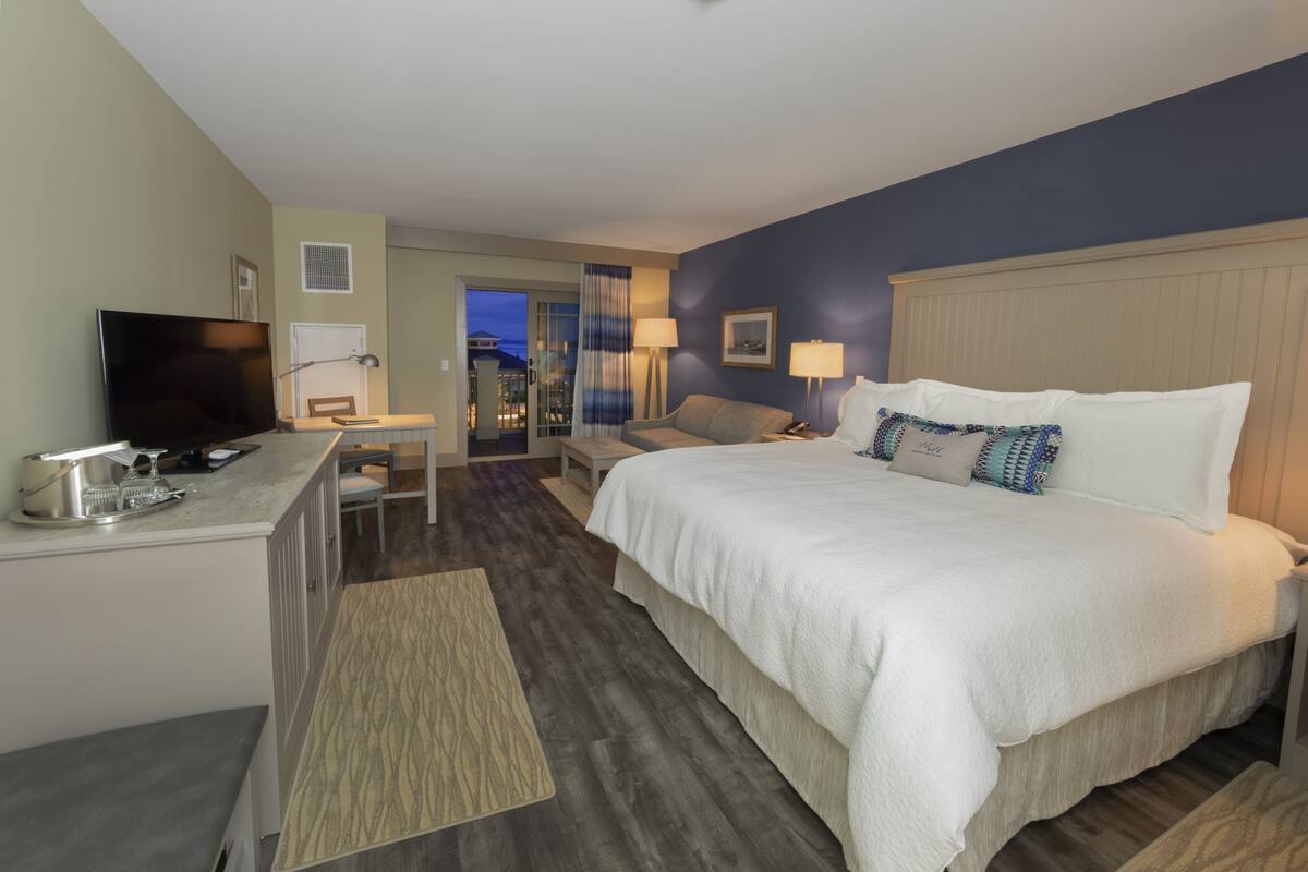 Habitación de hotel con cama, escritorio, televisor y vistas al exterior.
