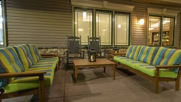 A cozy outdoor seating area with striped sofas and chairs, a wooden table, and stone accents.