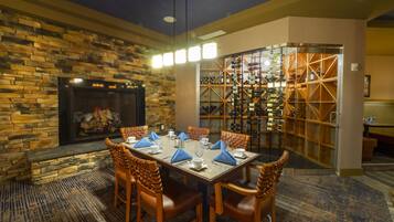A dining area with a stone fireplace, a wine rack, and a carpeted floor.