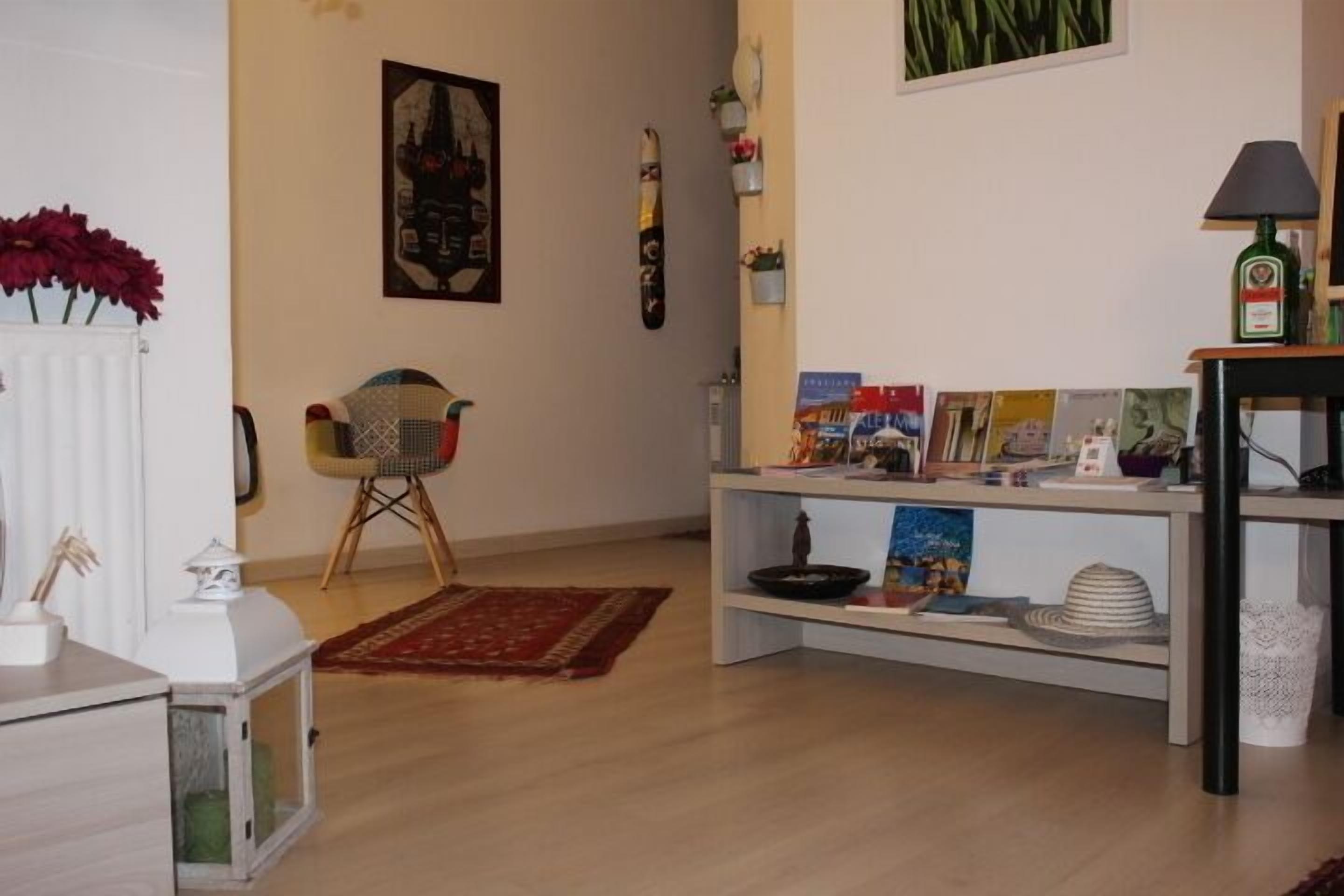A living room with a white radiator, a chair, a bookshelf, and a table with a lamp.