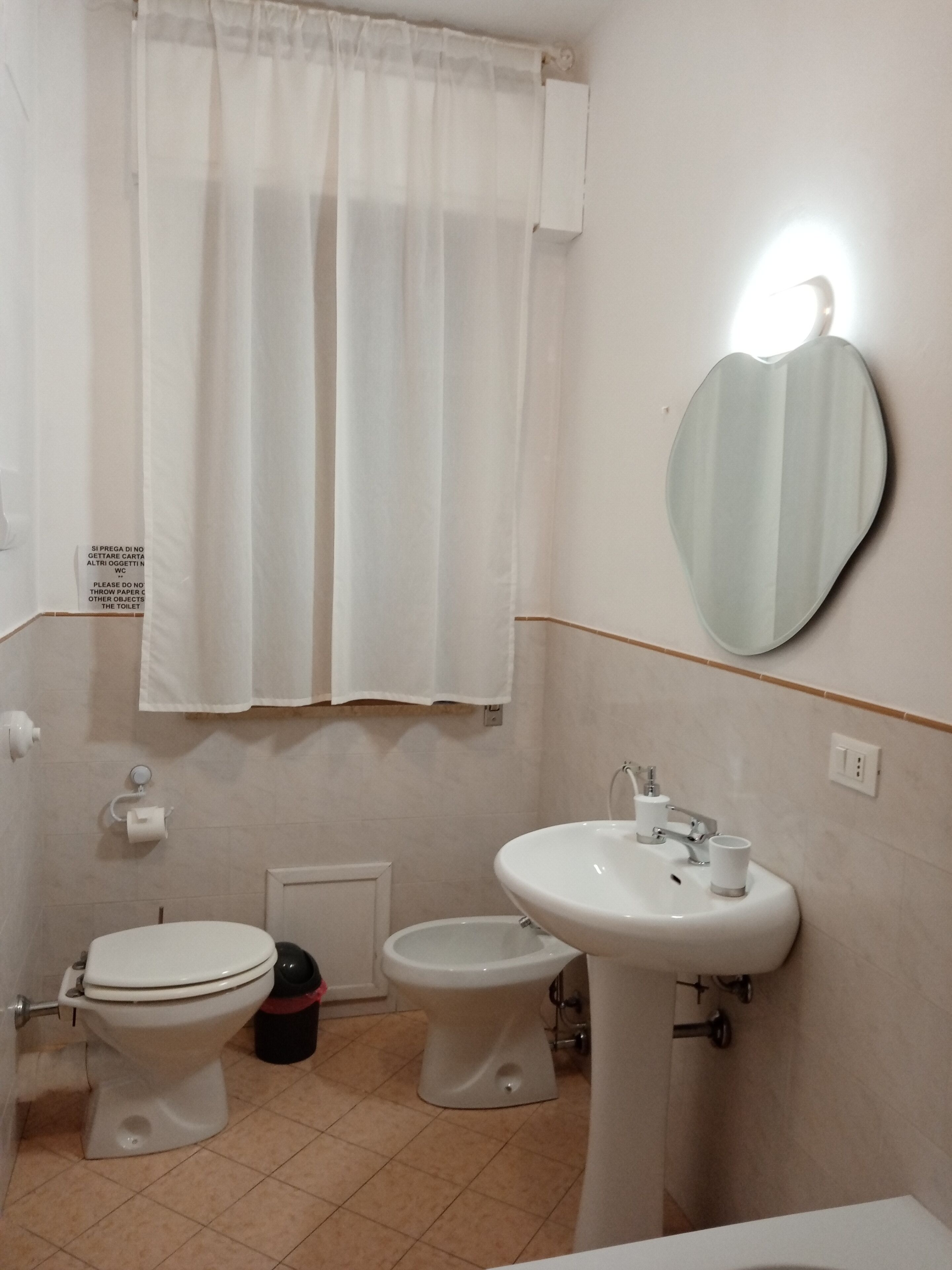 Un baño con dos inodoros, un lavabo, un espejo y una cortina de ducha.