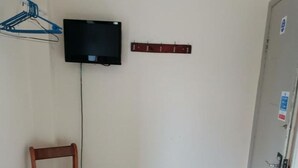 A room with a wooden chair, a television mounted on the wall, and a door with a sign. - Swan Inn, Heathrow Airport (Staines)