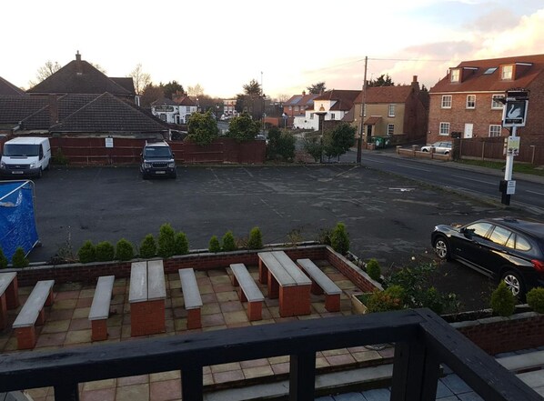 A parking area with a row of benches and a building with a sign that reads "The Great". - Swan Inn, Heathrow Airport (Staines)