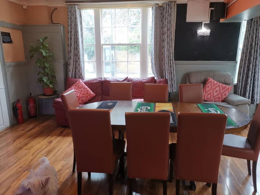 Un comedor acogedor con una mesa de madera y sillas a juego, un sofá con cojines rojos y una planta en maceta.