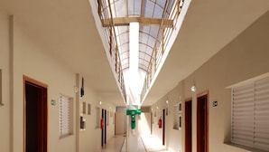 Un largo pasillo de hotel angosto con un pasillo central, puertas a ambos lados y un tragaluz en la parte superior.