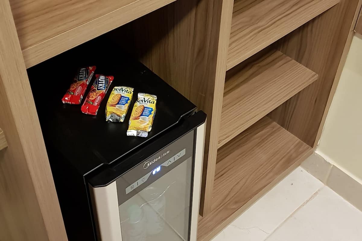 Zona cuina amb frigorífic integrat i armari de fusta amb prestatgeries.